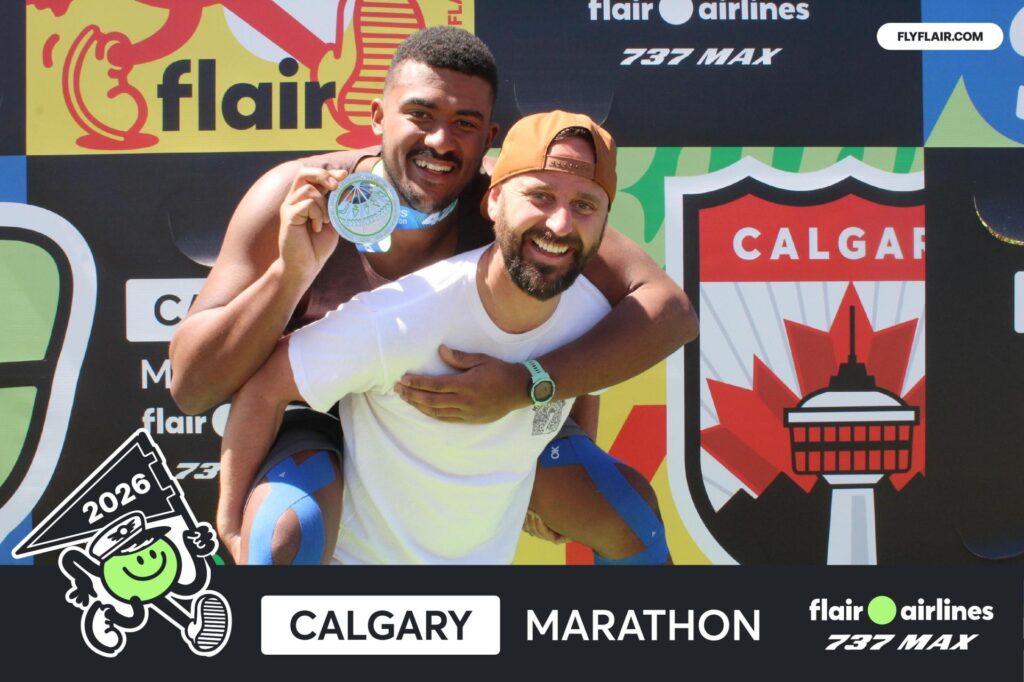 One man holding anothe man on his back posing for a photo at Calgary Marathon